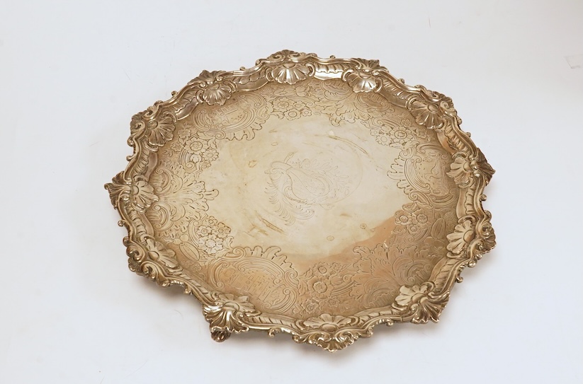 A late George II provincial shaped circular silver salver, by William Partis, Newcastle 1754?, with engraved crest and later embossed decoration, on three lions paw feet, diameter 31.4cm, 32.3oz. Condition - fair